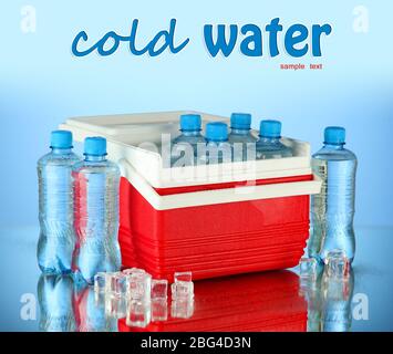 Reisekühlschrank mit Wasserflaschen und Eiswürfeln, auf blauem Hintergrund Stockfoto