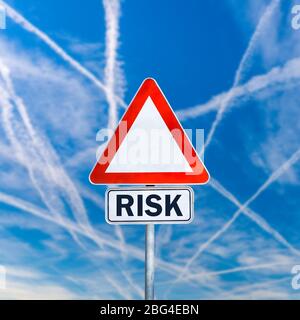 Dreieckige leere Straßenschild mit Wort Risiko in zusätzlichen Raum unten geschrieben. Über blauem Himmel mit sich kreuzenden Kondensstreifen.