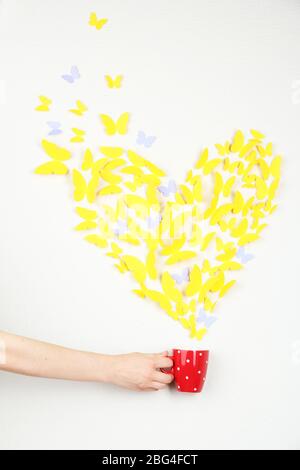 Papier gelben Schmetterling in Form von Herz fliegen aus Tasse Stockfoto