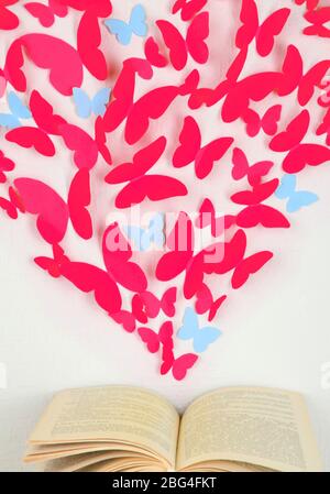 Papierschmetterlinge in Form von Herz fliegen aus Buch Stockfoto