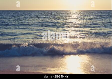 Wellen, die bei Sonnenuntergang an der Küste krachen Stockfoto