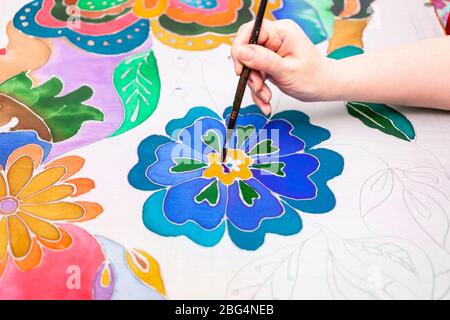 Künstler malt Blume auf weiße Seidenleinwand in kalten Kontur Batik Technik Stockfoto