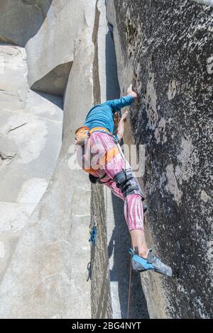Kletterer schaut auf seine Füße in rosa Beinung auf der Nase im Yosemite Stockfoto