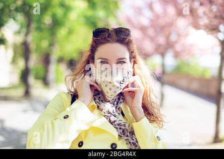 Positive junge Frau, die während der Coronavirus-Pandemie im Frühjahr Maske trägt Stockfoto