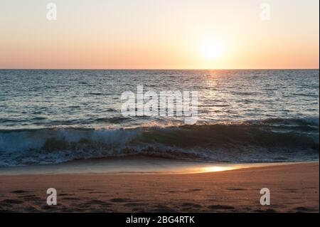 Wellen brechen zusammen, wenn die Sonne über dem Pazifischen Ozean in Mexiko untergeht Stockfoto