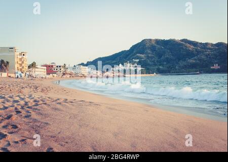 Kleiner Stadtstrand in Mexiko bei Sonnenuntergang mit Berg im Hintergrund Stockfoto