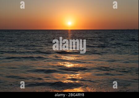 Orangefarbene Sonne geht über dunklem Wasser in Mexiko an der Pazifikküste unter Stockfoto