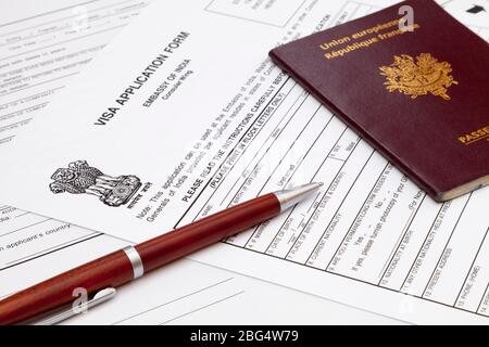 Ein Kugelschreiber und ein französischer Pass auf der Oberseite eines indischen Visumsantrags. Stockfoto