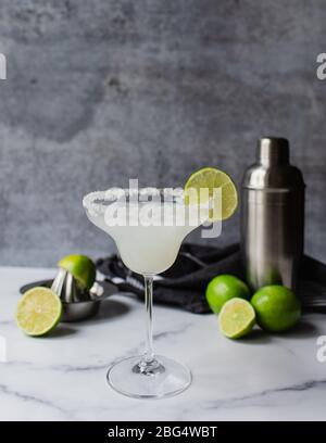 Nahaufnahme des margarita Cocktails mit Limetten und Shaker auf Marmorplatte Stockfoto