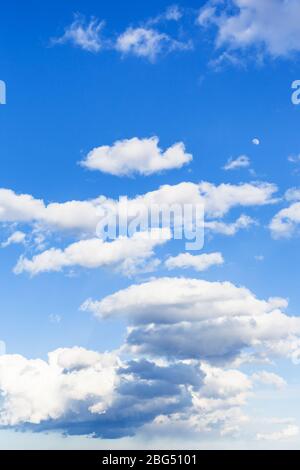 Niedrige dunkle Regenwolken und hohe weiße Wolken am blauen Himmel am Märztag Stockfoto