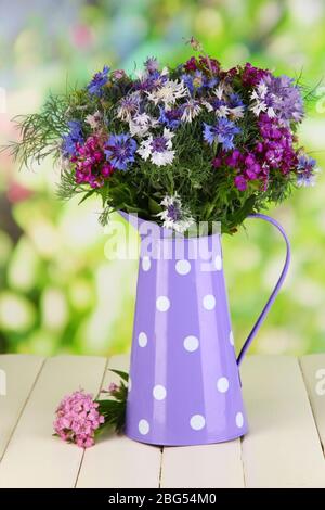 Schönes Bouquet in Krug auf Holztisch auf natürlichem Hintergrund Stockfoto