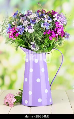 Schönes Bouquet in Krug auf Holztisch auf natürlichem Hintergrund Stockfoto