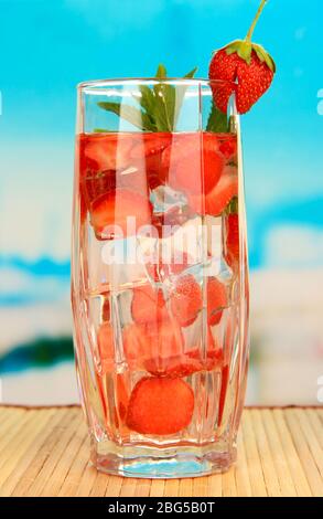 Glas Fruchtgetränk mit Eiswürfeln auf blauem Hintergrund Stockfoto