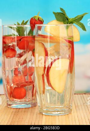 Gläser Fruchtgetränke mit Eiswürfeln auf blauem Hintergrund Stockfoto