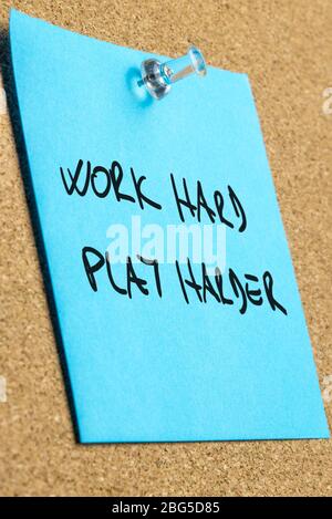 Idiom Arbeit hart spielen härter auf blauen Post geschrieben es Papier auf Kork Bulletin Board festgeklemmt. Stockfoto