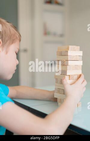 Kleiner Junge spielt mit Holz umweltfreundliche Brettspiel. Konzept. Heimspiele in Quarantäne gestellt. Innen Stockfoto