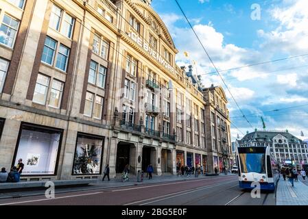 Amsterdam, Niederlande - 7. September 2018: Fassade des Kaufhauses De Bijenkorf mit Straßenbahn und Menschen auf dem Dam-Platz in Amsterdam, N Stockfoto