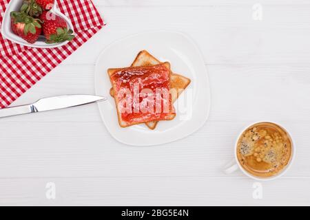 Erdbeeren, Toast mit Erdbeermarmelade und Kaffee auf dem weißen Tisch. Stockfoto