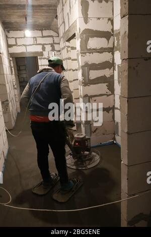 Der Arbeiter mit den speziellen Werkzeugen führt den Sand-Zementestrich für die Heizung und die Fußbodenheizung aus.2020 Stockfoto