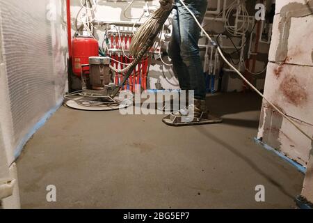 Der Arbeiter mit den speziellen Werkzeugen führt den Sand-Zementestrich für die Heizung und die Fußbodenheizung aus.2020 Stockfoto