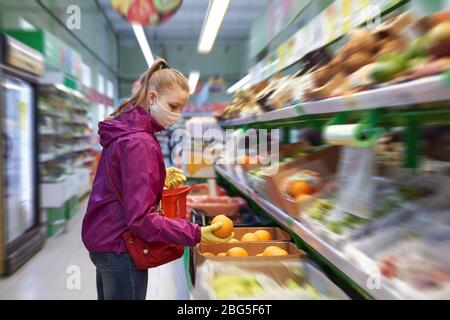 Frau in selbstgemachter Maske und Schutzhandschuhen wählt während der Coronavirus COVID-19-Epidemie Lebensmittel im Supermarkt Stockfoto