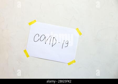 Die Inschrift covid-19 auf einem an die Wand geklebten Blatt. Das Konzept der Selbstisolierung. Coronavirus, stoppen Sie die Ausbreitung der Infektion. 2019-ncov. Stockfoto