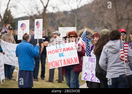 Helena, Montana - 19. April 2020: Rot-köpfige Frau mit einem Schild, das wegen der Schließung von Coronavirus-Geschäften wieder zur Arbeit zurückkehren möchte. Protest A Stockfoto