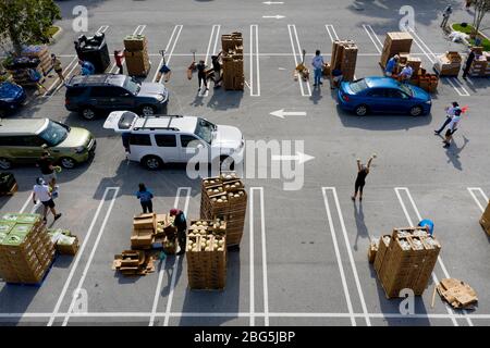 West Palm Beach, Florida, USA. April 2020. Die Autos stehen in einem Drive-up-Lebensmittelverteilungszentrum auf dem Parkplatz der Palm Beach Outlets. Die Menschen erhalten eine Woche Versorgung mit Eiweiß, frischen Produkten, Eiern, Milch und anderen wichtigen Gütern. Die Spenden sind auf 800 Autos auf einer First come first serve Basis jeden Montag begrenzt. Palm Beach Outlets hat sich mit der Ernährung von Süd-Florida zusammengetan, um denjenigen zu helfen, die während der Coronavirus-Pandemie kämpfen. Kredit: Gregg Lovett/ZUMA Wire/Alamy Live News Stockfoto