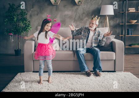 Foto von alten Großvater wenig hübsch Enkelin sitzen bequeme Sofa Uhr zeigen schauspielende Fee Kostüm gute Laune Aufenthalt Haus Quarantäne Sicherheit modern Stockfoto