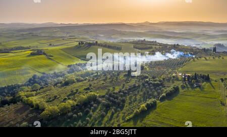 Luftbild der toskanischen Landschaft bei nebeligem Sonnenaufgang am frühen Morgen in der Toskana, Italien, April. Stockfoto