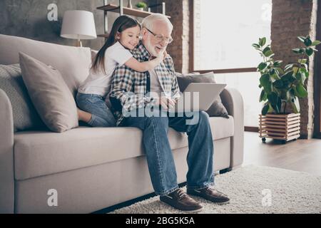 Profil Foto von lustigen alten Großvater kleine Enkelin sitzen Sofa bleiben Haus Quarantäne Sicherheit Film ansehen Notebook sprechen skype Verwandten modernes Design Stockfoto