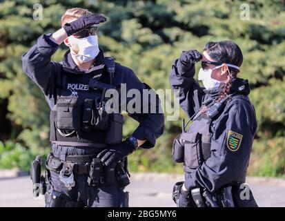 20. April 2020, Sachsen, Chemnitz: Polizisten mit Gesichtsmasken überwachen eine Kundgebung des rechtsextremen Vereins Pro Chemnitz vor dem Karl-Marx-Denkmal. Die Kundgebung fand unter strengen Bedingungen statt: Die Teilnehmerzahl war auf 15 begrenzt, außerdem war keine Demonstration erlaubt und es musste ein Mindestabstand von zwei Metern zwischen den Teilnehmern eingehalten werden. Außerdem musste eine Gesichtsmaske getragen werden und das Ereignis durfte nicht länger als eine Stunde dauern. Pro Chemnitz hielt das Treffen unter dem Motto "Wir wollen raus! End State Willkür' ursprünglich registriert Stockfoto