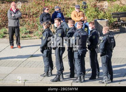 20. April 2020, Sachsen, Chemnitz: Polizisten mit Gesichtsmasken überwachen eine Kundgebung des rechtsextremen Vereins Pro Chemnitz vor dem Karl-Marx-Denkmal. Die Kundgebung fand unter strengen Bedingungen statt: Die Teilnehmerzahl war auf 15 begrenzt, außerdem war keine Demonstration erlaubt und es musste ein Mindestabstand von zwei Metern zwischen den Teilnehmern eingehalten werden. Außerdem musste eine Gesichtsmaske getragen werden und das Ereignis durfte nicht länger als eine Stunde dauern. Pro Chemnitz hielt das Treffen unter dem Motto "Wir wollen raus! End State Willkür' ursprünglich registriert Stockfoto