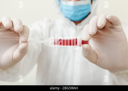Coronavirus, Kovid-19-Bluttest in den Händen der Ärzte. Arzt im medizinischen Schutzanzug, biologische Gefahr, medizinische Maske, Schutzhandschuhe auf weiß Stockfoto