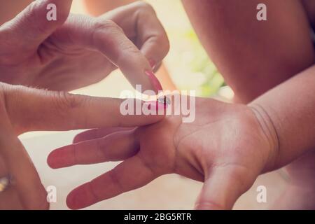 Nahaufnahme einer Mutter und ihrer Kinder Hand mit einem rot gefleckten Marienkäfer oder Marienkäfer, Retro-Effekt verblichenen Look. Stockfoto