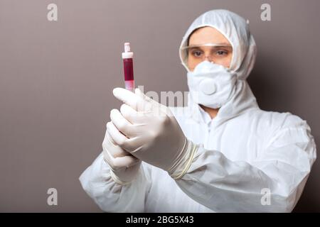 Coronavirus, Kovid-19-Bluttest in den Händen der Ärzte. Arzt im medizinischen Schutzanzug, biologische Gefahr, medizinische Maske, Schutzhandschuhe auf weiß Stockfoto