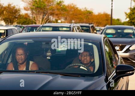 West Palm Beach, Florida, USA. April 2020. Frauen warten in ihrem Auto an einem Drive-up-Lebensmittelverteilungszentrum auf dem Parkplatz der Palm Beach Outlets. Die Menschen erhalten eine Woche Versorgung mit Eiweiß, frischen Produkten, Eiern, Milch und anderen wichtigen Gütern. Die Spenden sind auf 800 Autos jeden Montag begrenzt. Palm Beach Outlets hat sich mit der Ernährung von Süd-Florida zusammengetan, um denjenigen zu helfen, die während der Coronavirus-Pandemie kämpfen. Kredit: Gregg Lovett/ZUMA Wire/Alamy Live News Stockfoto