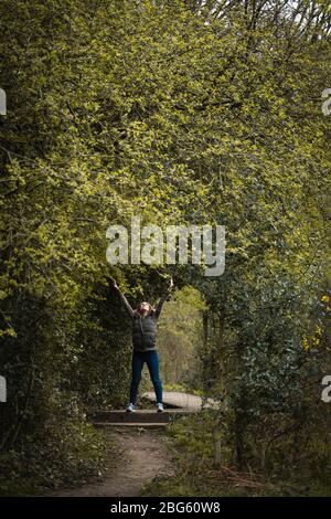 Eine junge Frau stand unter einem Torbogen, der von Bäumen auf dem Land geschaffen wurde Stockfoto