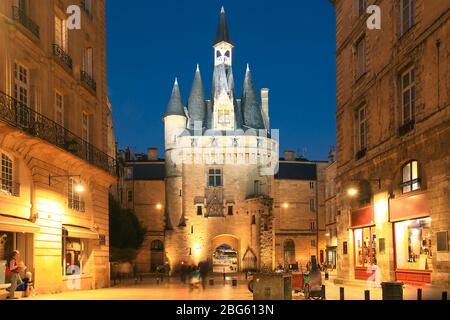 Blick auf die historische Porte Cailhau bei Nacht mit Menschen beim Abendessen auf der Terrasse des Restaurants in Bordeaux, Frankreich Stockfoto