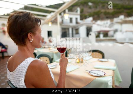 Reife schöne touristische Frau trinken Rotwein Sangria während sitzen im Restaurant im Freien Stockfoto