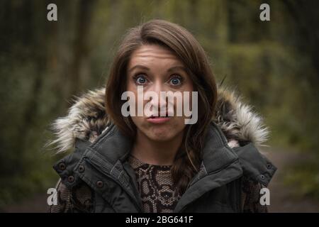 Eine junge attraktive Frau, die auf dem Land ein dummes Gesicht aus der Nähe zieht Stockfoto