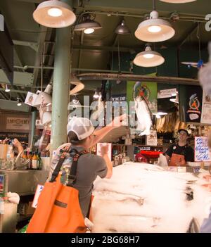 Mann wirft Fisch auf Pike Place Fish Market Stockfoto