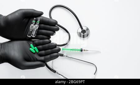 Hände in schwarzen medizinischen Handschuhen mit Pillen und Ampullen auf weißem Hintergrund. Behandlungskonzept für kardiovaskuläre Erkrankungen. Kopierbereich Stockfoto