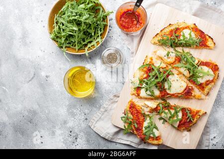 Hausgemachte glutenfreie Cauliflower Pizza Kruste Teig mit Tomaten Marinara-Sauce, Mozzarella-Käse auf grauem Hintergrund.Gemüsealternative für Low-Car Stockfoto