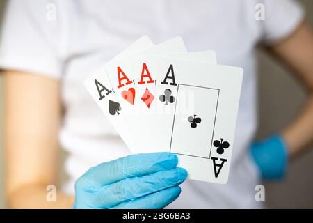 Junge Frau mit Einweghandschuhen, die Karten hält - vier Asse, vier von einer Art Stockfoto
