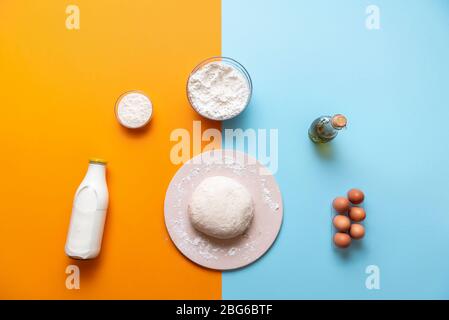 Sauerteig auf einem Backstein, umgeben von Backzutaten. Oben mit Brotsorten auf einem bunten Tisch. Arbeitsbereich für das Backen. Stockfoto