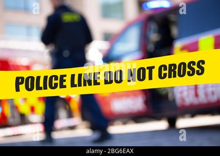 Flache Tiefenschärfe Bild der Polizei Band mit Aktion von verschwommenen Polizisten und Rettungswagen im Hintergrund. Stockfoto