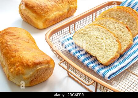 Ein paar selbstgemachte Weißbrot auf einem Kühlregal mit einem Tuch auf weißem Tisch Stockfoto