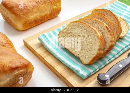 Ein paar Rutsche hausgemachtes Weißbrot auf einem Koch Holzbrett mit einem Tuch auf weißem Tisch Stockfoto