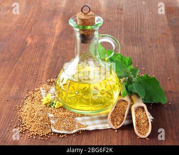 Glas Senföl und Samen mit Senfblume auf Holzhintergrund Stockfoto